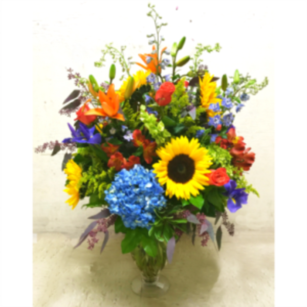 Colorful mixed bouquet in a clear glass vase with sunflowers and lilies