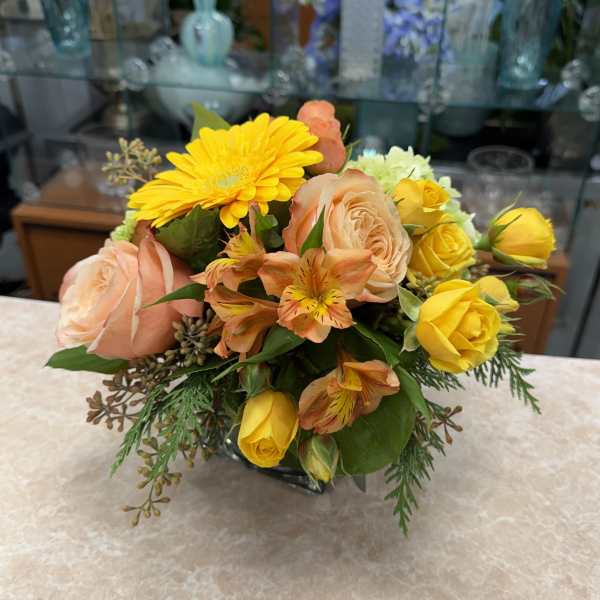 Bouquet of yellow and peach flowers in a low vase
