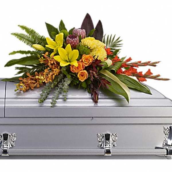 Vibrant yellow, orange, and pink casket spray on a silver casket