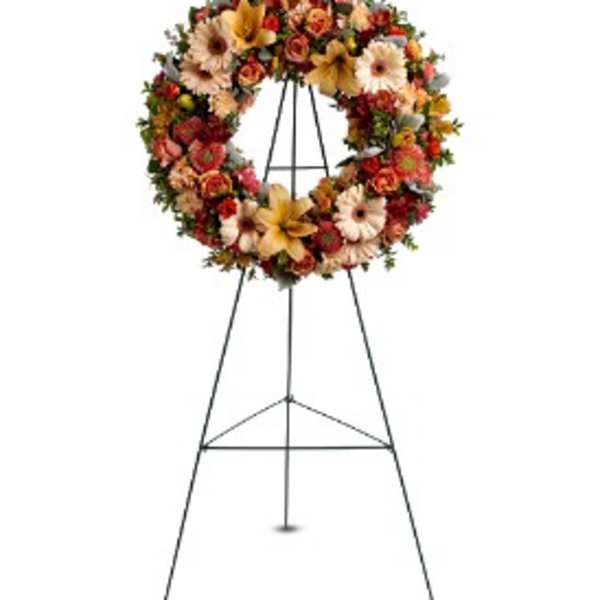 Standing wreath of peach and orange flowers with lilies and gerberas on a metal easel