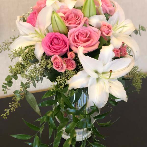 Pink roses and white lilies arranged in a glass vase