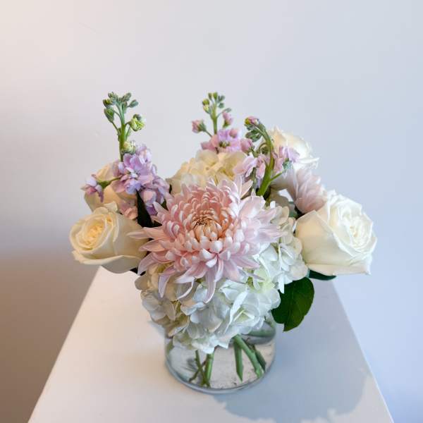 Pink and white flowers arranged in a clear glass vase