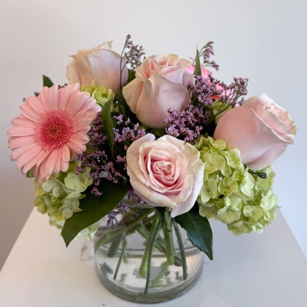 Pink roses and a gerbera daisy in a clear glass vase