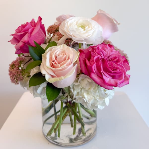 Pink and white roses with hydrangeas in a clear glass vase