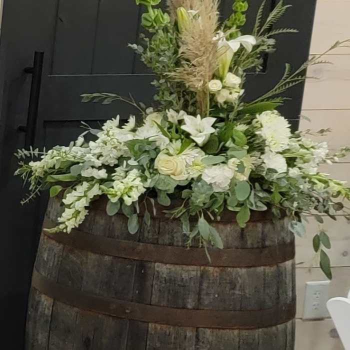 White floral arrangement in a wooden barrel with tall grasses