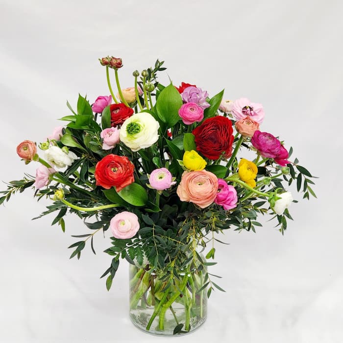 Mixed bouquet of colorful ranunculus in a clear glass vase