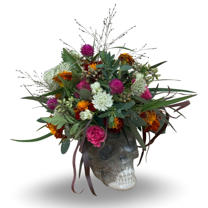 Floral arrangement in a skull-shaped container with bright mixed blooms