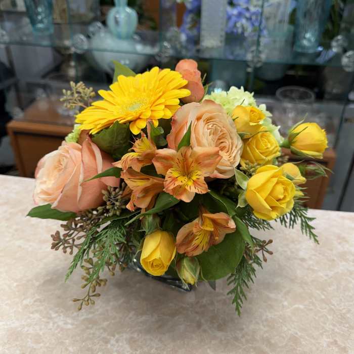 Bouquet of yellow and peach flowers in a low vase