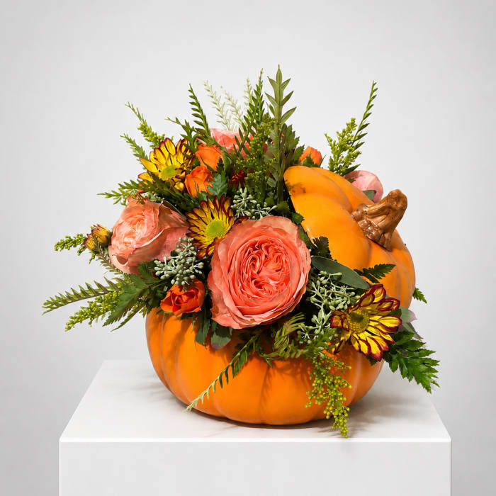 Orange pumpkin filled with pink and yellow flowers