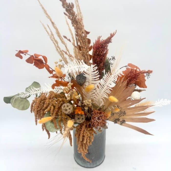 Dried floral arrangement in a ribbed metal vase