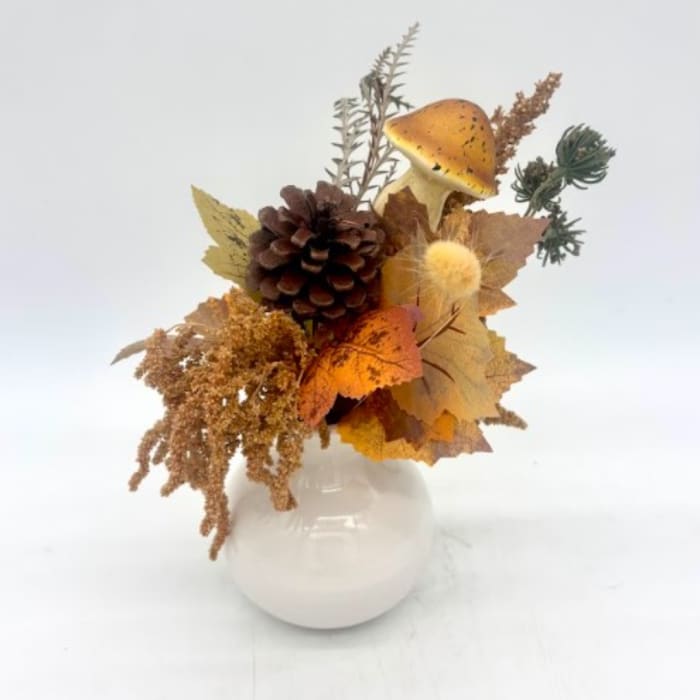 Autumn arrangement with pinecone, mushroom, and fall leaves in a white vase