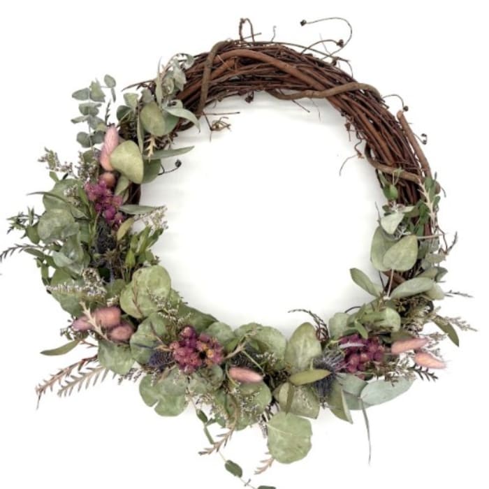 Floral wreath with eucalyptus, pink accents, and a brown twig base