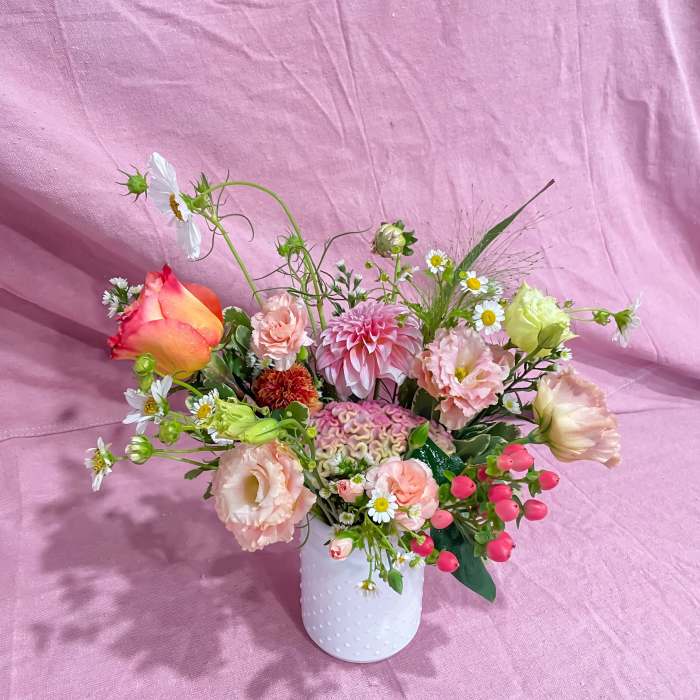 Mixed bouquet in a white textured vase with pink, peach, and white blooms