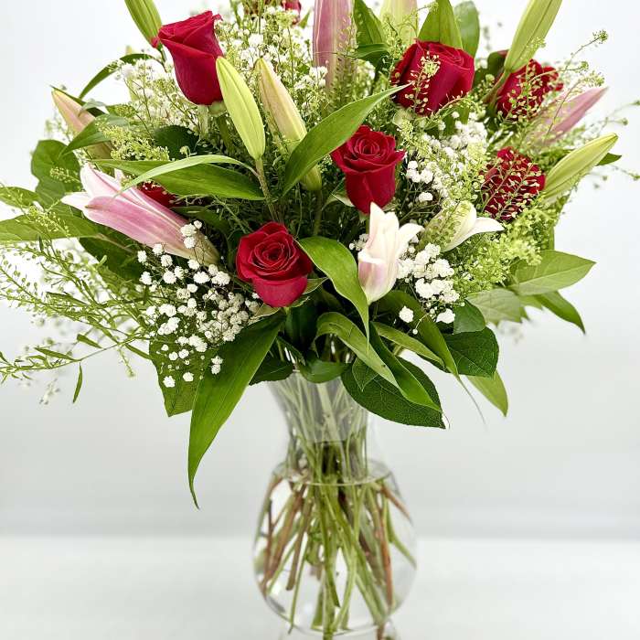 Red roses and pink lilies in a clear glass vase