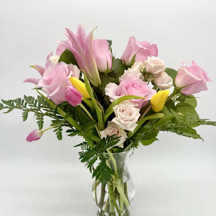 Pink roses and tulips arranged in a clear glass vase