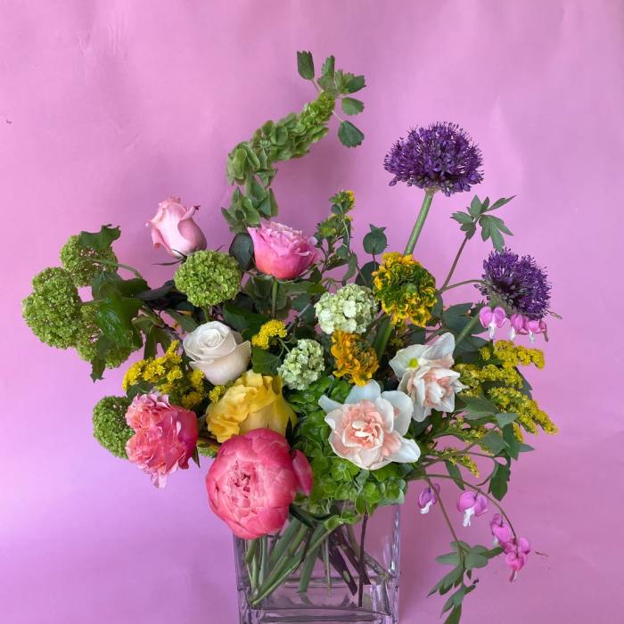 Mixed bouquet in a clear square vase with pink, yellow, white, and purple blooms