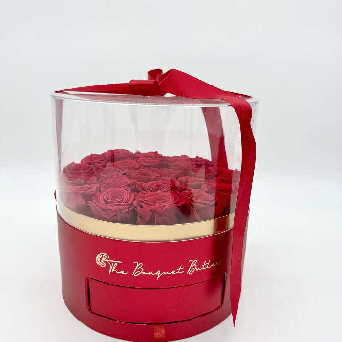 Red roses in a clear round gift box with a red ribbon