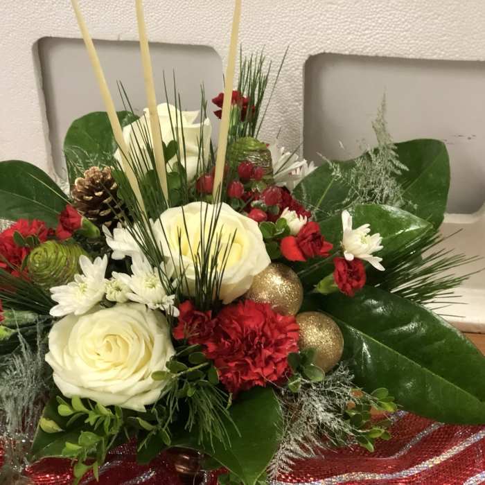 Holiday floral arrangement with white roses, red carnations, and gold ornaments