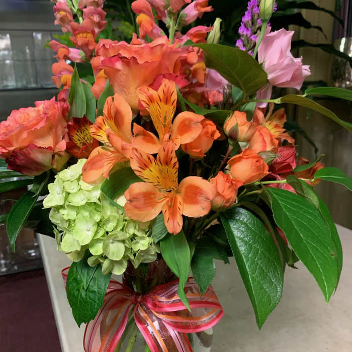 Colorful mixed bouquet in a glass vase with a ribbon bow