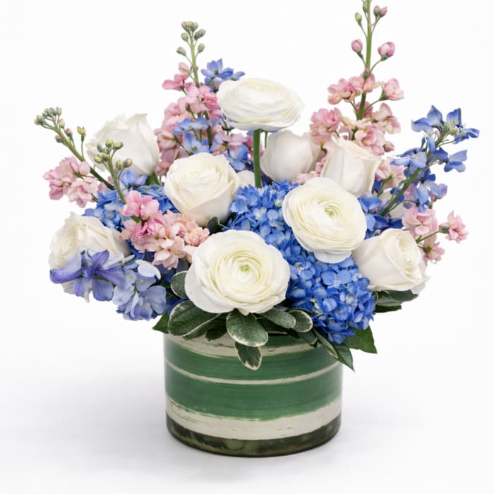 White roses and blue hydrangeas in a green striped vase