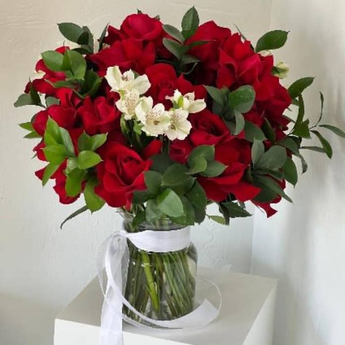 Bouquet of red roses with white flowers in a glass vase