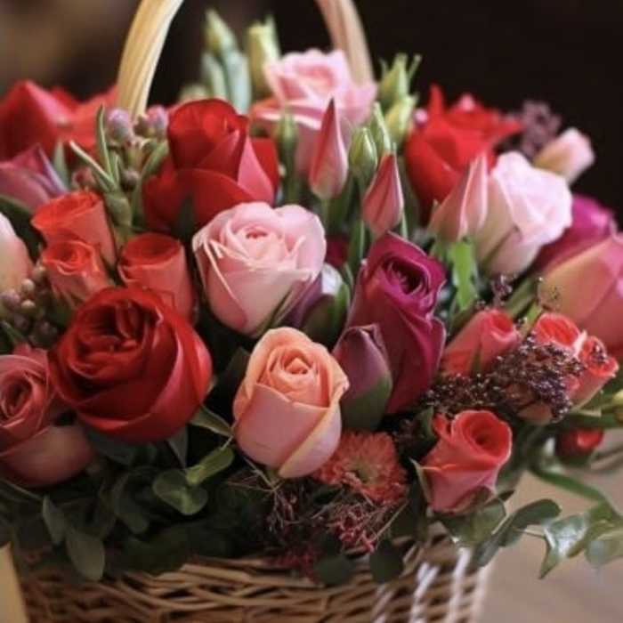 Basket of mixed roses and tulips in pink and red tones