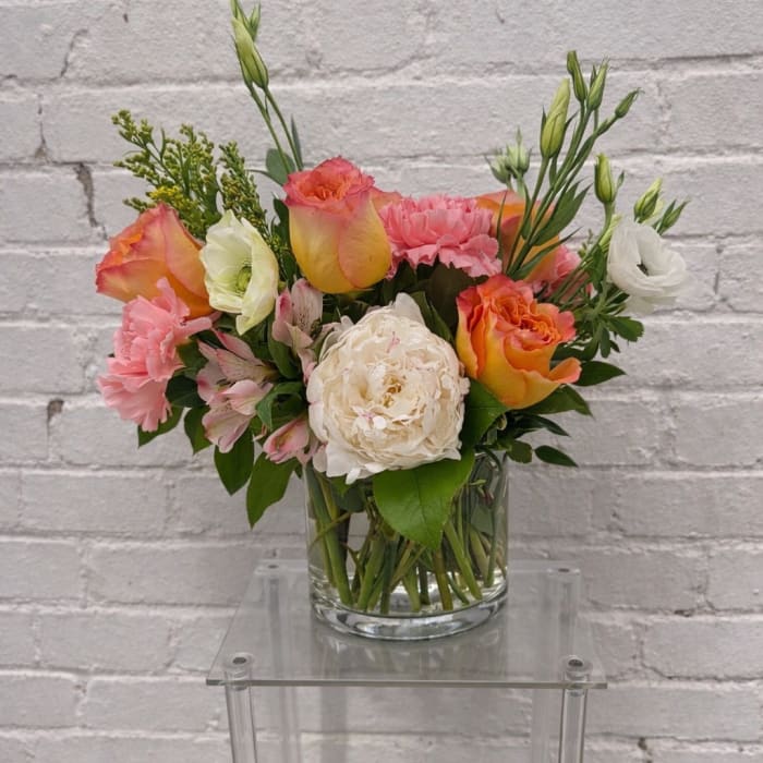 Mixed bouquet of pink, orange, and white flowers in a glass vase