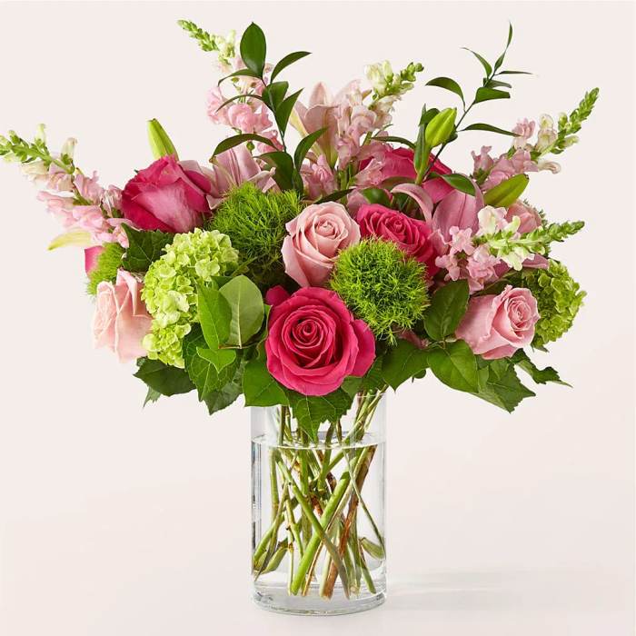 Pink roses, green hydrangeas, and snapdragons arranged in a clear glass cylinder vase
