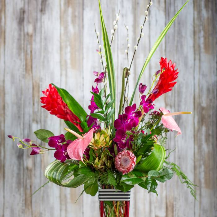 Tropical bouquet with pink orchids and red ginger in a glass vase
