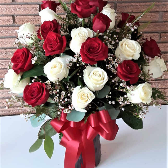 Bouquet of red and white roses with a red ribbon in a vase