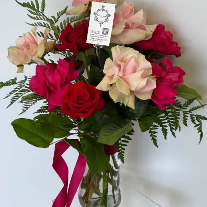Bouquet of red and blush roses in a glass vase with a pink ribbon
