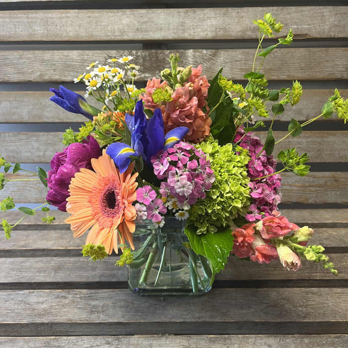 Colorful mixed bouquet in a clear glass vase with gerbera, iris, and hydrangea
