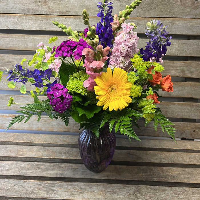 Colorful mixed flower arrangement in a dark glass vase
