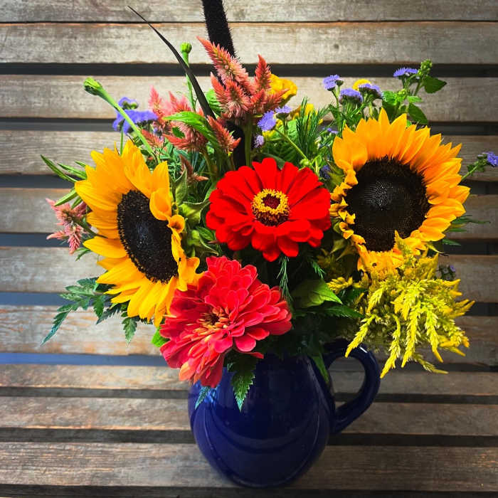 Bright mixed bouquet with sunflowers and zinnias in a blue mug