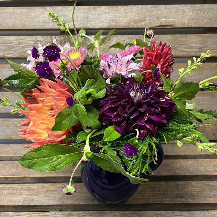 Colorful mixed bouquet in a dark vase with purple, pink, and coral blooms