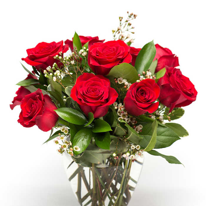 Red roses arranged in a clear glass vase with small white filler flowers