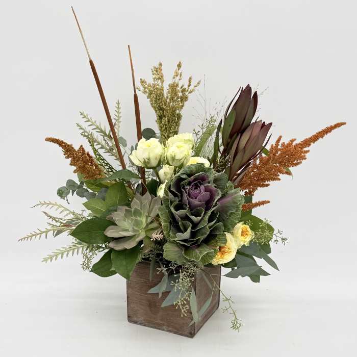 Mixed floral arrangement in a wooden box with purple and cream blooms
