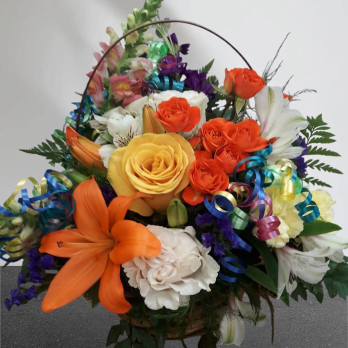 Colorful mixed flower basket with roses, lilies, and ribbon curls