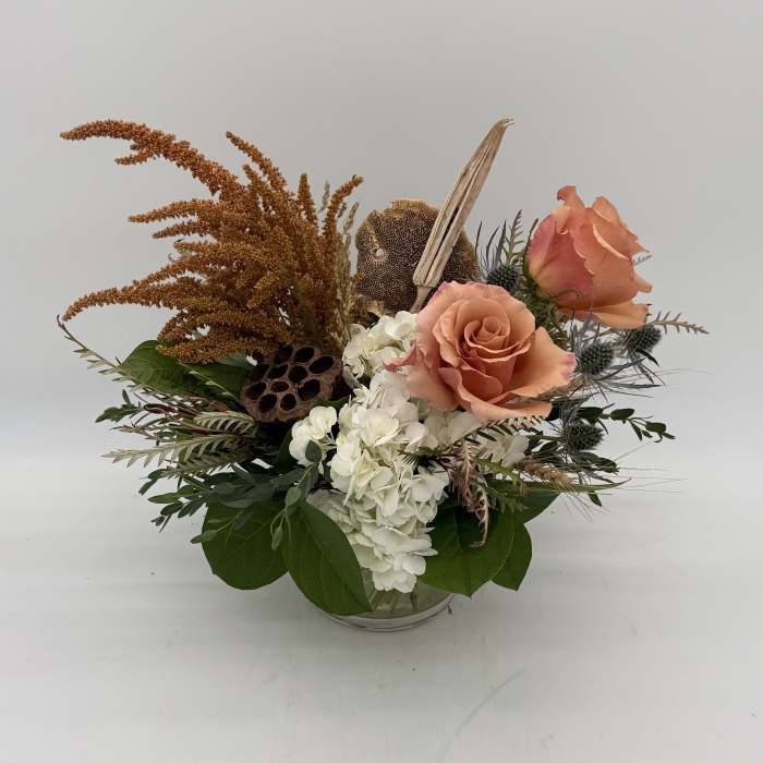 Peach roses and white hydrangeas in a glass bowl with dried accents