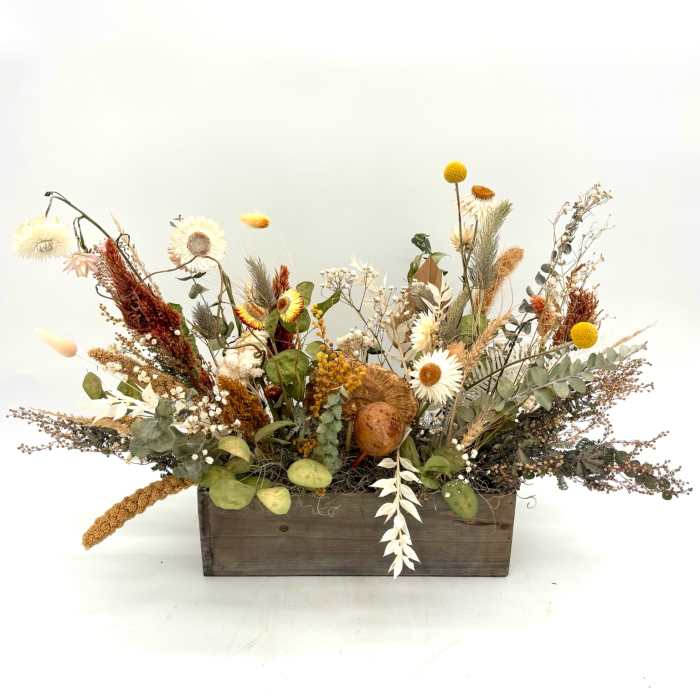 Dried floral arrangement in a wooden box with white and yellow blooms