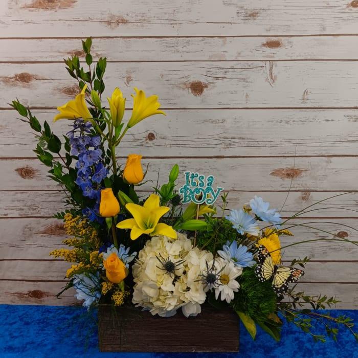 Mixed floral arrangement with yellow lilies, blue flowers, and white hydrangea in a wooden box