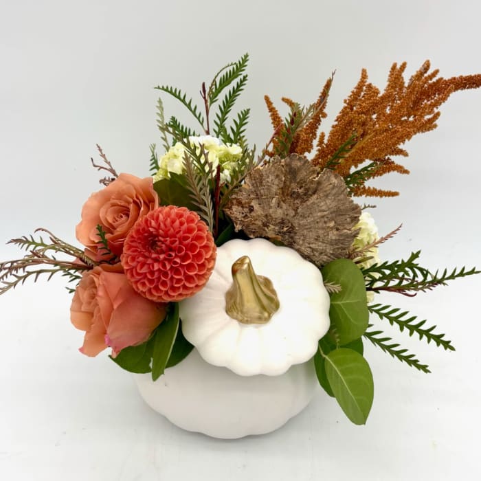 Floral arrangement in a white pumpkin-shaped vase with peach and coral blooms