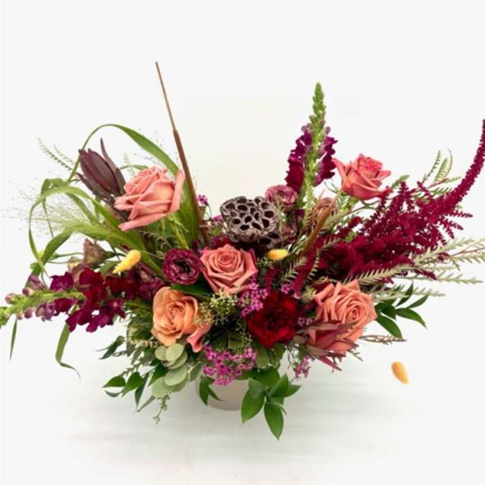 Pink roses and burgundy flowers arranged in a white vase