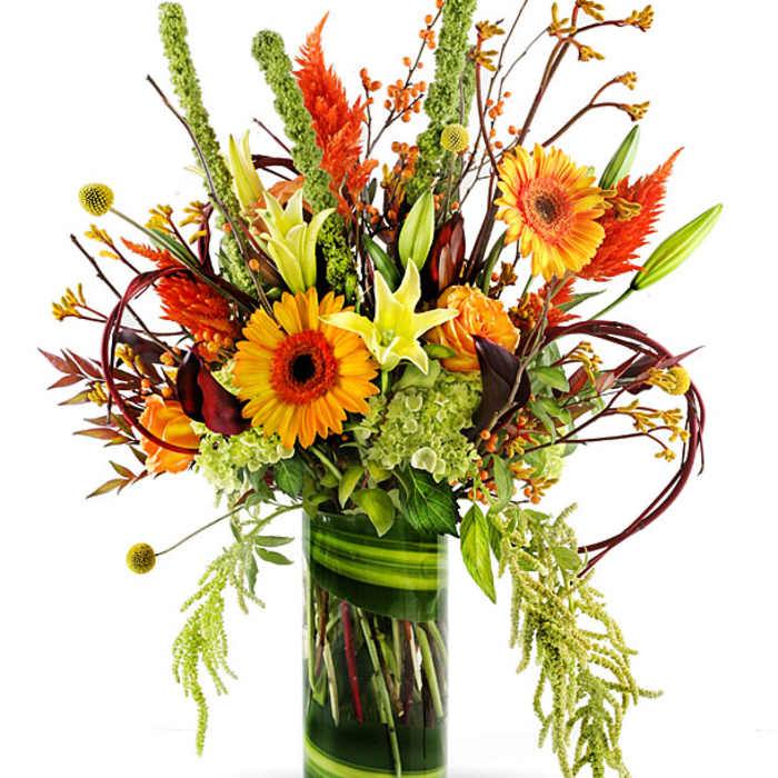 Tall autumn bouquet with orange gerbera daisies and lilies in a glass vase