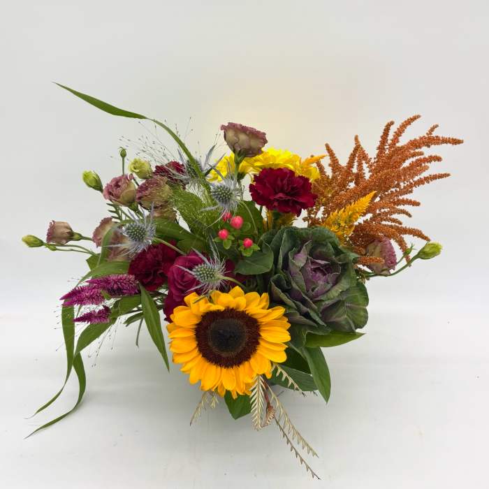 Mixed bouquet with a sunflower, burgundy blooms, and orange accents