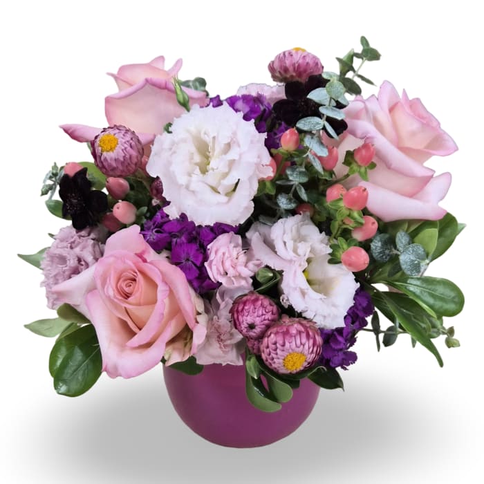 Pink roses and white blooms arranged in a purple vase