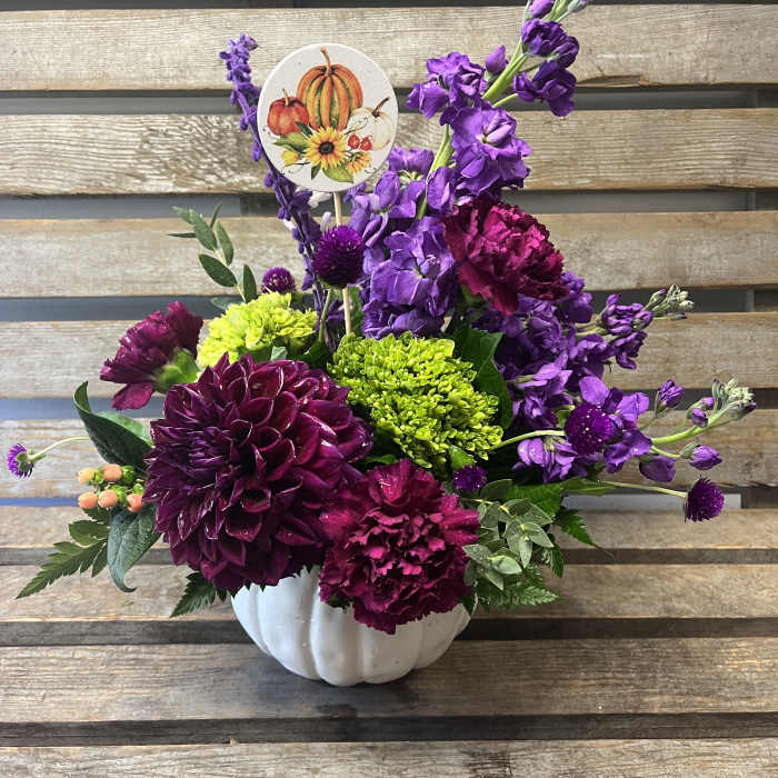 Purple and magenta floral arrangement in a white pumpkin vase