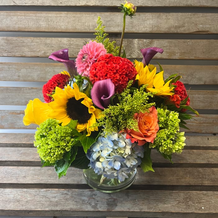 Mixed bouquet in a clear glass vase with sunflowers, calla lilies, and hydrangea