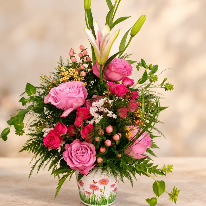 Pink roses and lilies arranged in a decorated white pot