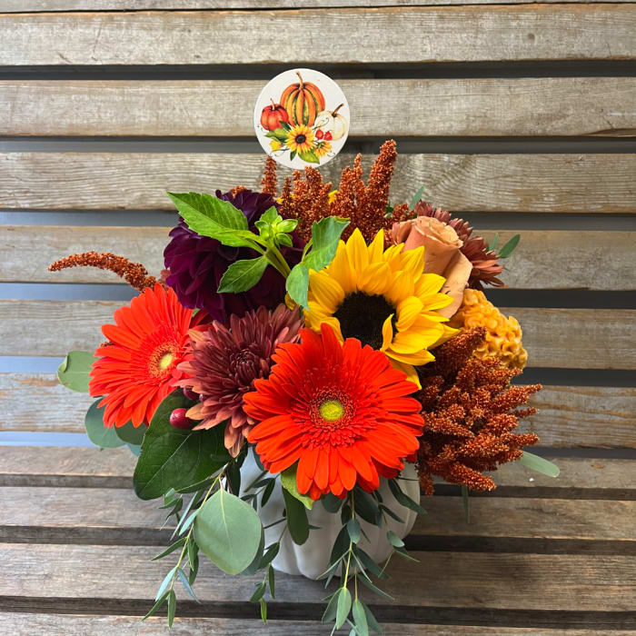 Fall bouquet with sunflowers, gerbera daisies, and a pumpkin pick in a white vase